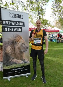 A man standing next to a Born Free banner holding his London Marathon medal