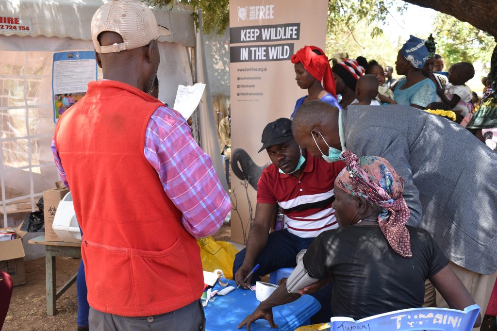 A woman sits with a blood pressure monitor on her arm at a medical camp in Kenya