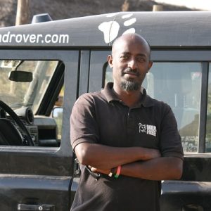 A headshot of Bereket Girma standing in front of a Born Free vehicle