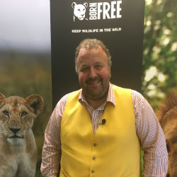 James Lewis standing in front of a Born Free banner