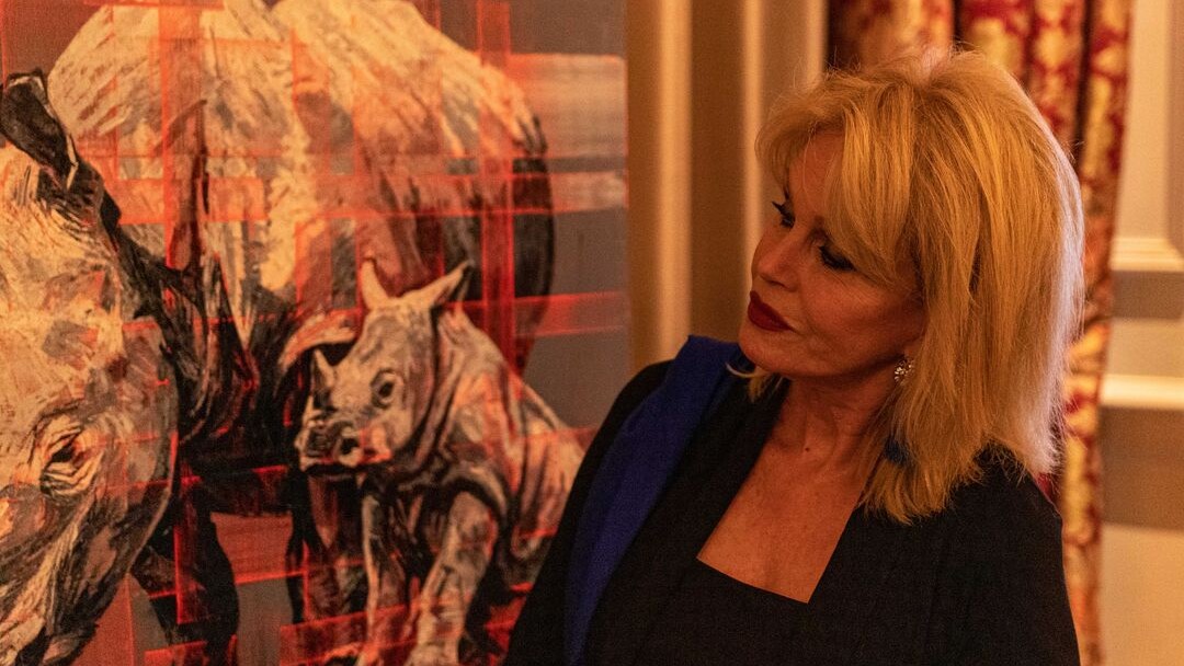 A photo of Joanna Lumley looking at a painting of a rhino