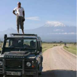 Norah Njiraini standing on top of a vehicle in front of a snowy mountain