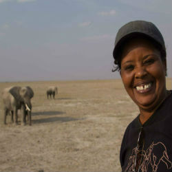 Norah Njiraini standing in front of wild elephants in the savannah