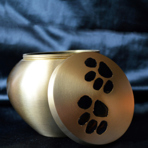 A gold urn with a black paw print on the side
