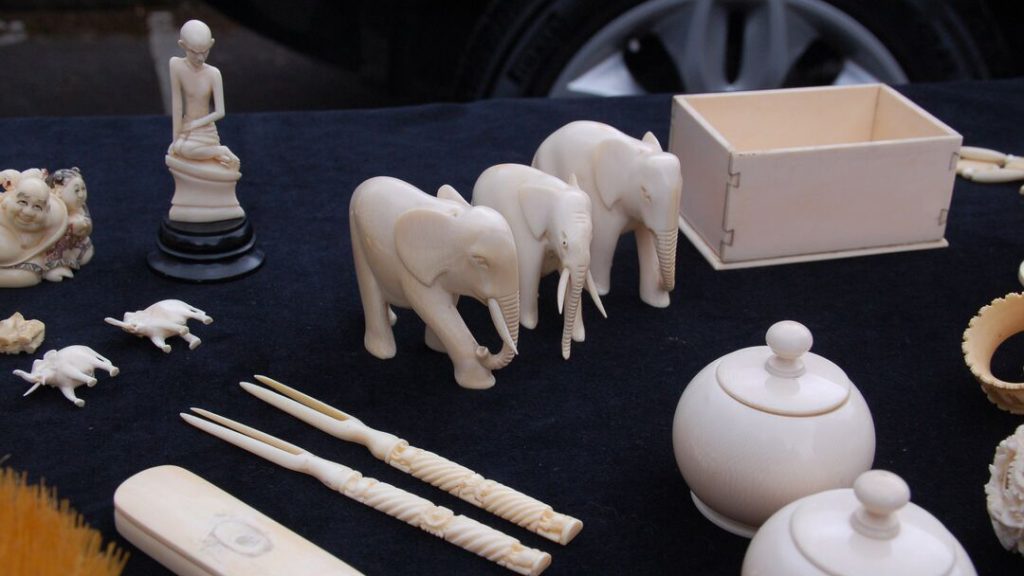 A selection of items carved from ivory, including elephant ornaments, laid out on a blue cloth