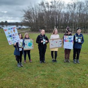 A group of young people with home made banners, meeting with a police officer.