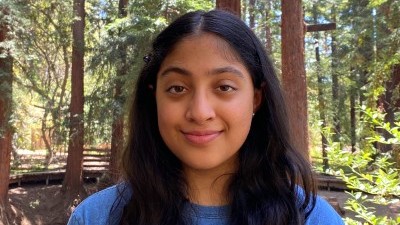 A photo of Nikita Dhawan standing in a forest