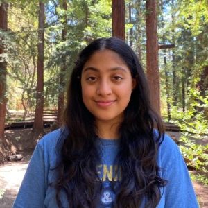 A photo of Nikita Dhawan standing in a forest