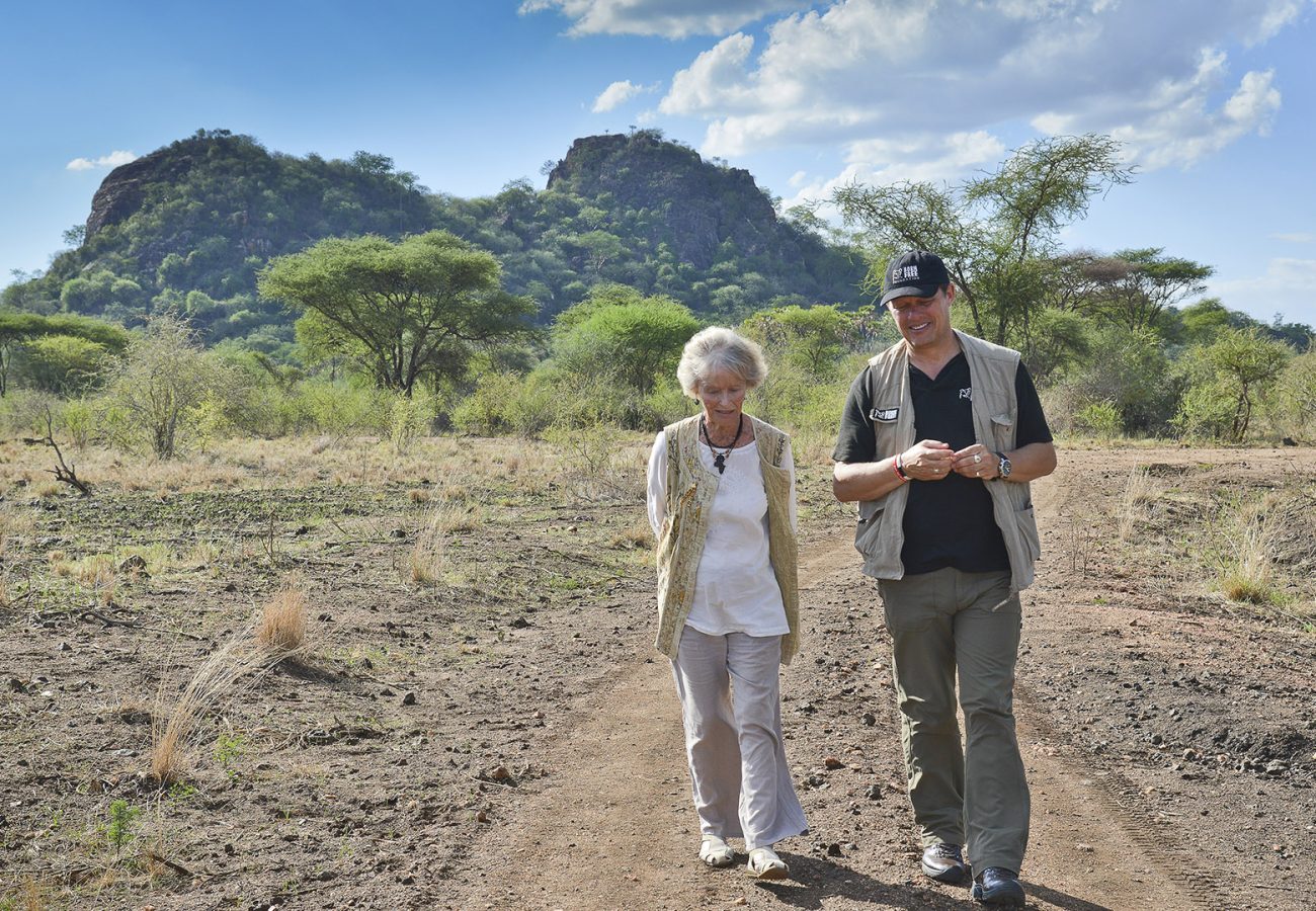 Virginia McKenna and Will Travers walking in front of a mountain