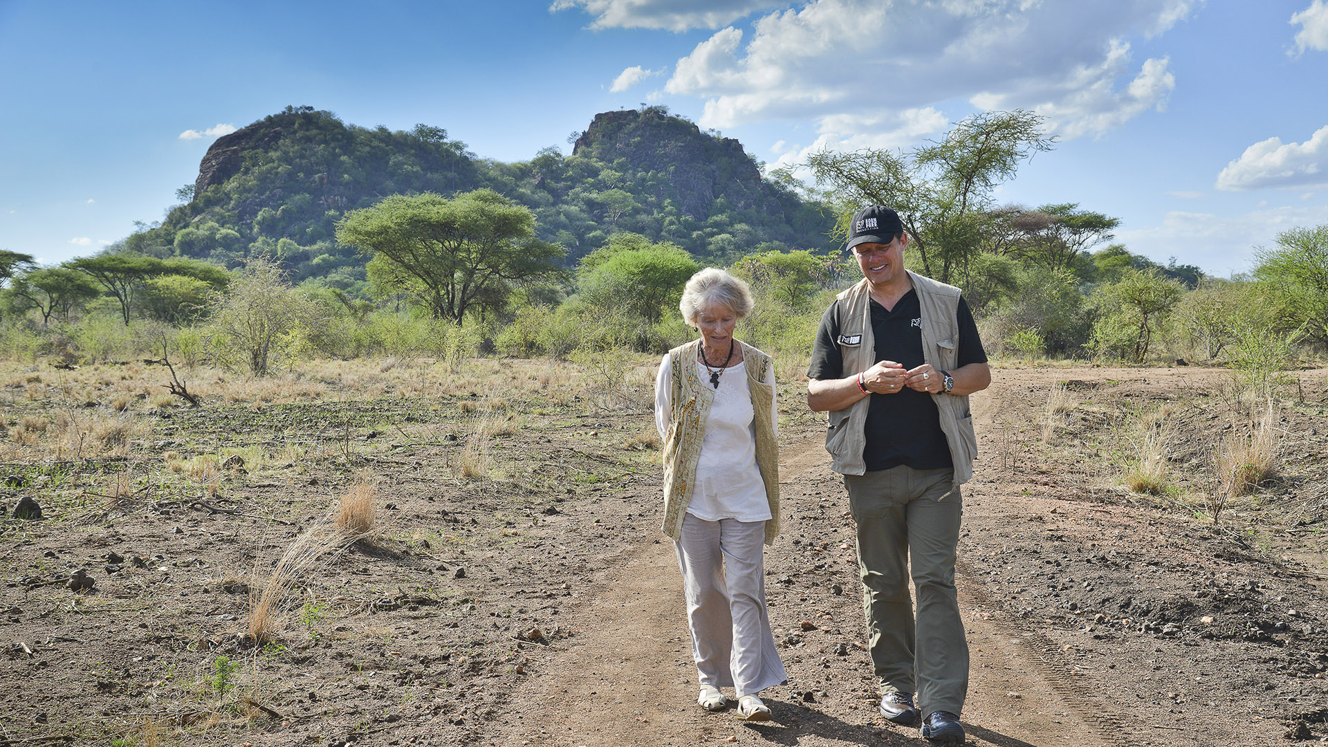 Virginia McKenna and Will Travers walking in front of a mountain