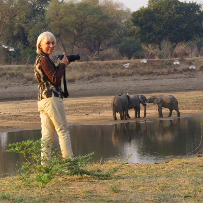 Carol Barrett stood with a camera in front of 3 elephants