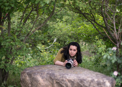 Diana Rudenko leaning over a large rock with a camera