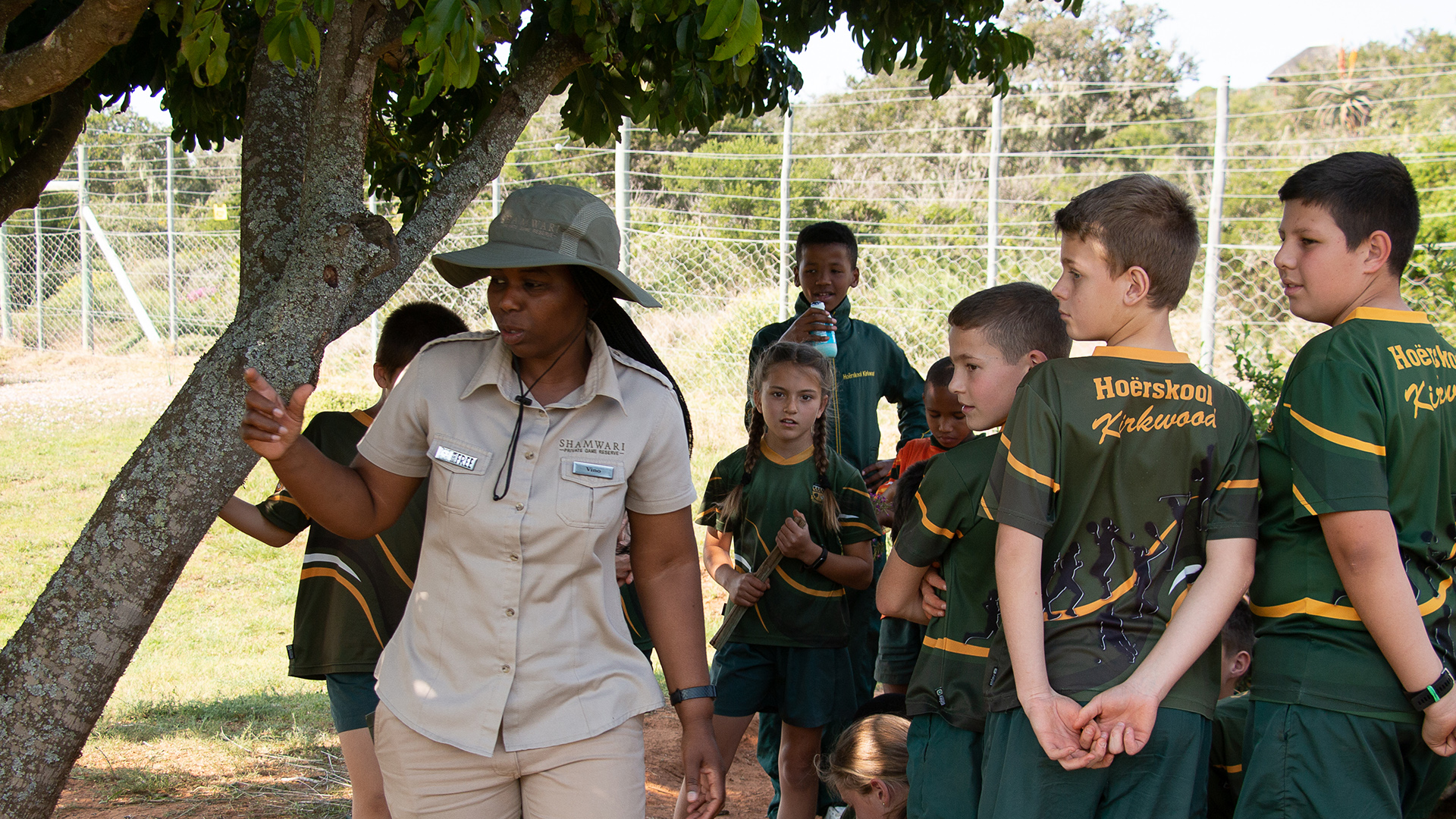A woman in Born Free uniform with South African school children in school uniform