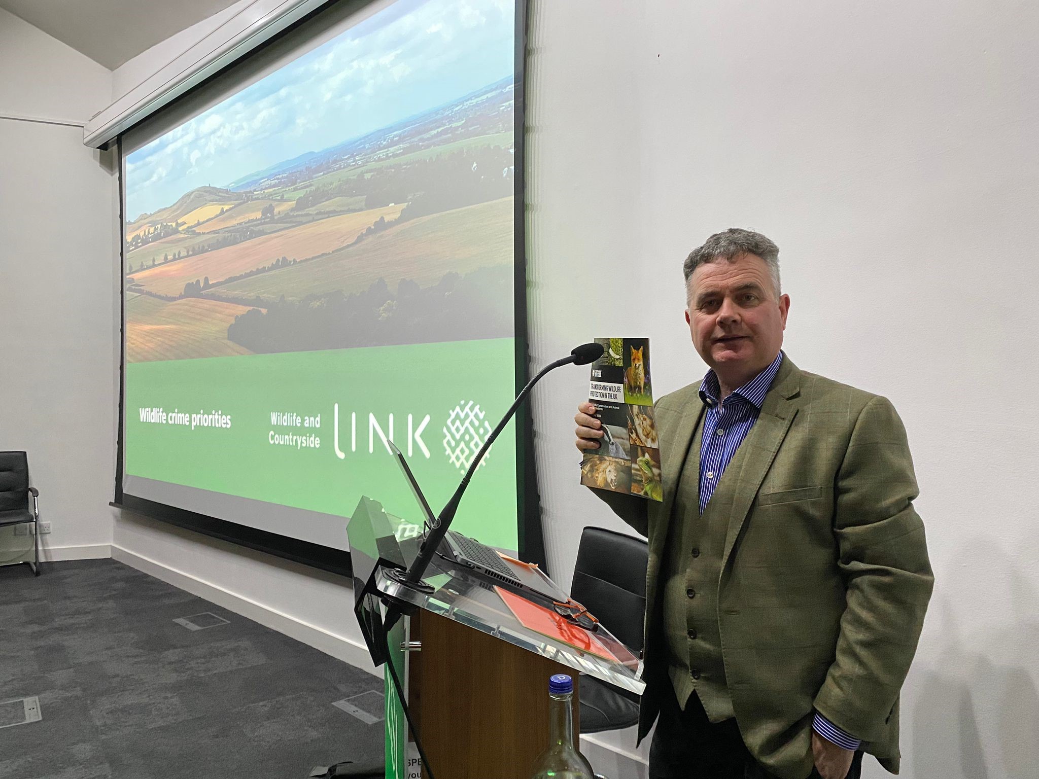 Born Free UK Policy Advisor Dominic Dyer stood in front of a projector screen, holding a copy of the Wildlife Manifesto