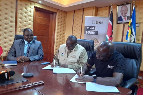 Three men sitting around a table signing documents