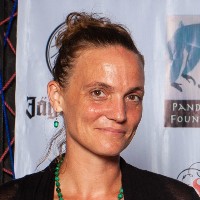 A head and shoulders portrait of a white woman with her hair tied back, taken at an event.