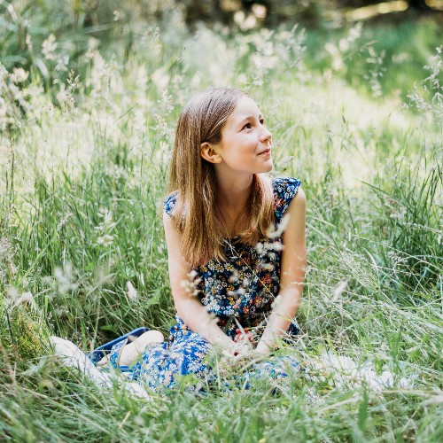 Thea Caine sitting in a meadow