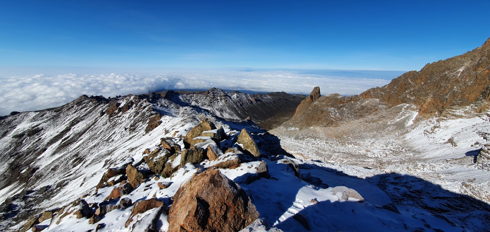 A photo of the summit of Mount Kenya with blue skies and snow-capped mountains