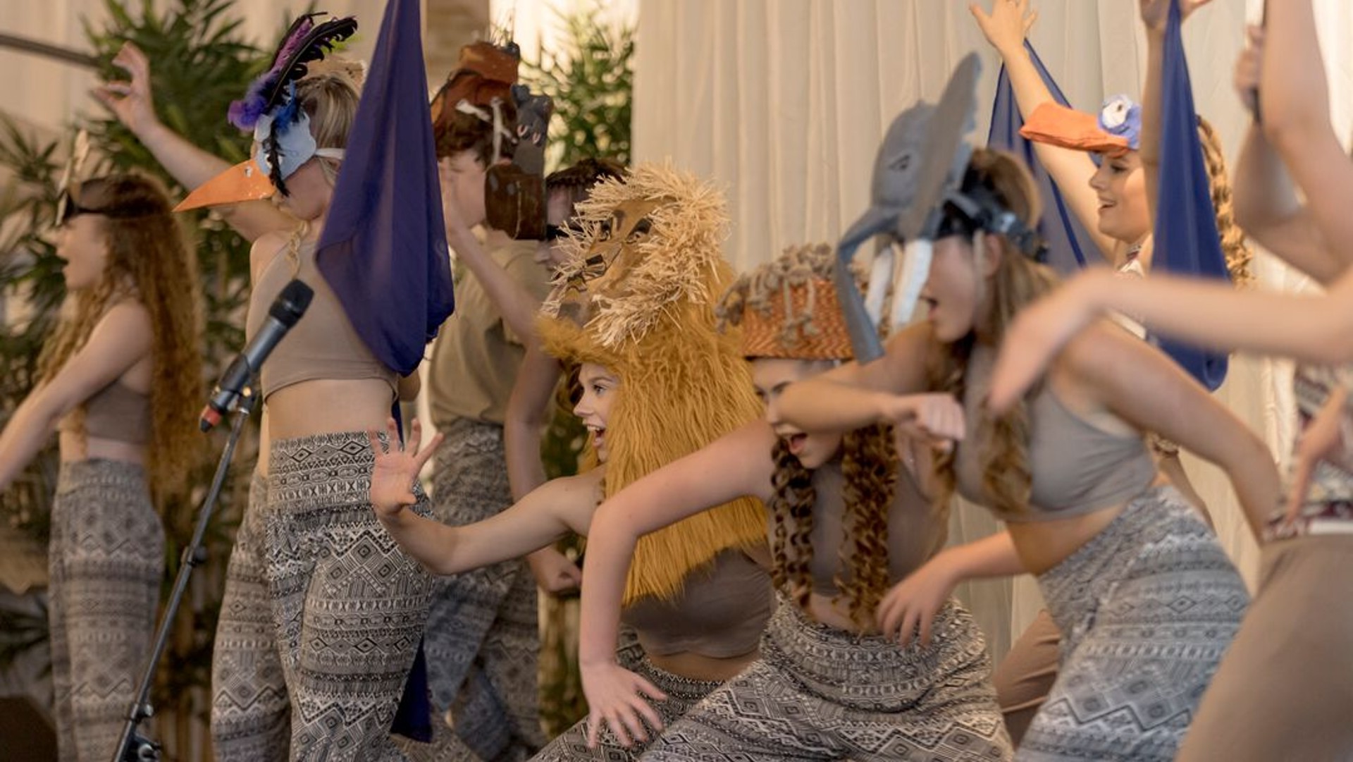 A group of young people dancing on stage wearing lion masks