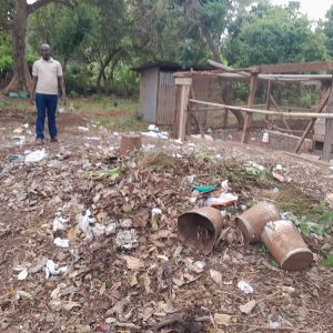 A man standing next to a rubbish-filled area of land