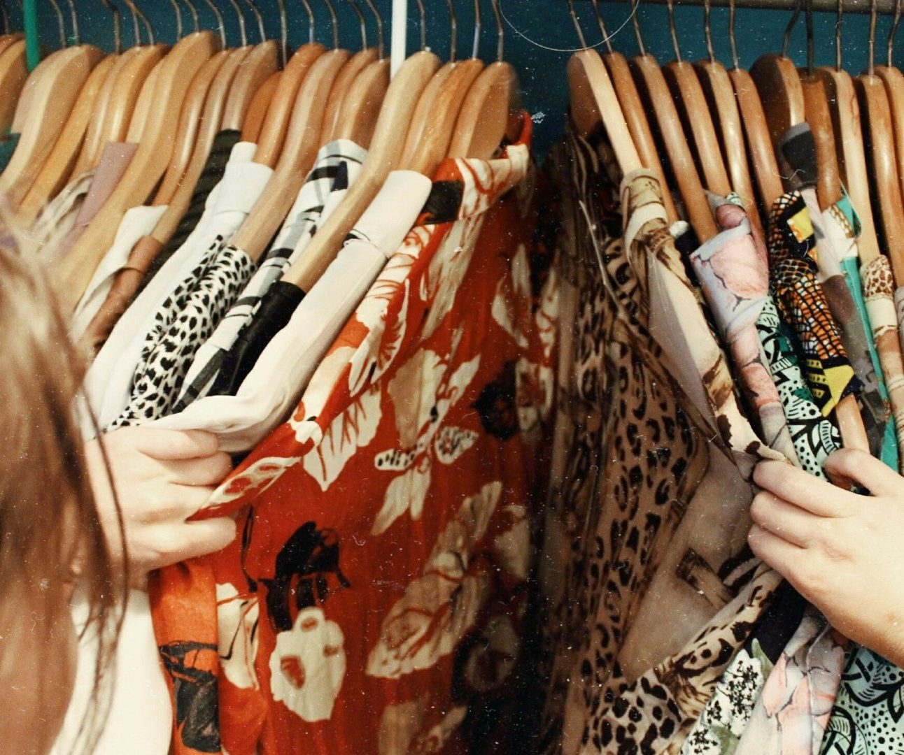 A rail of colourful shirts and blouses on wooden hangers