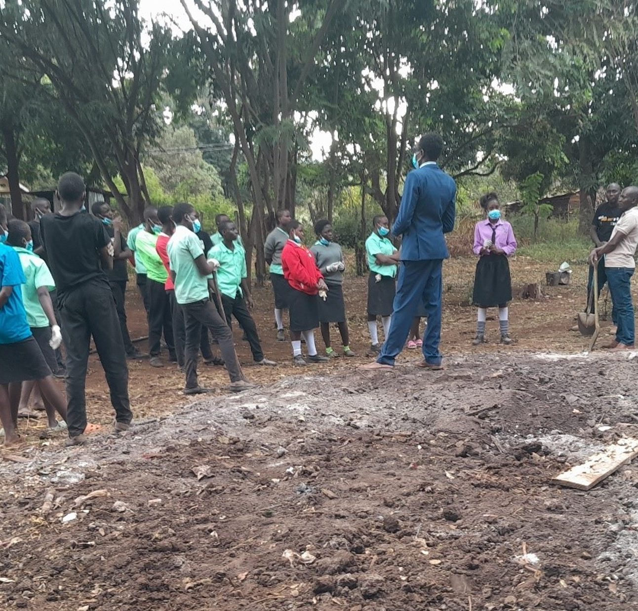 A group of school children standing next to an area of land which they have cleared