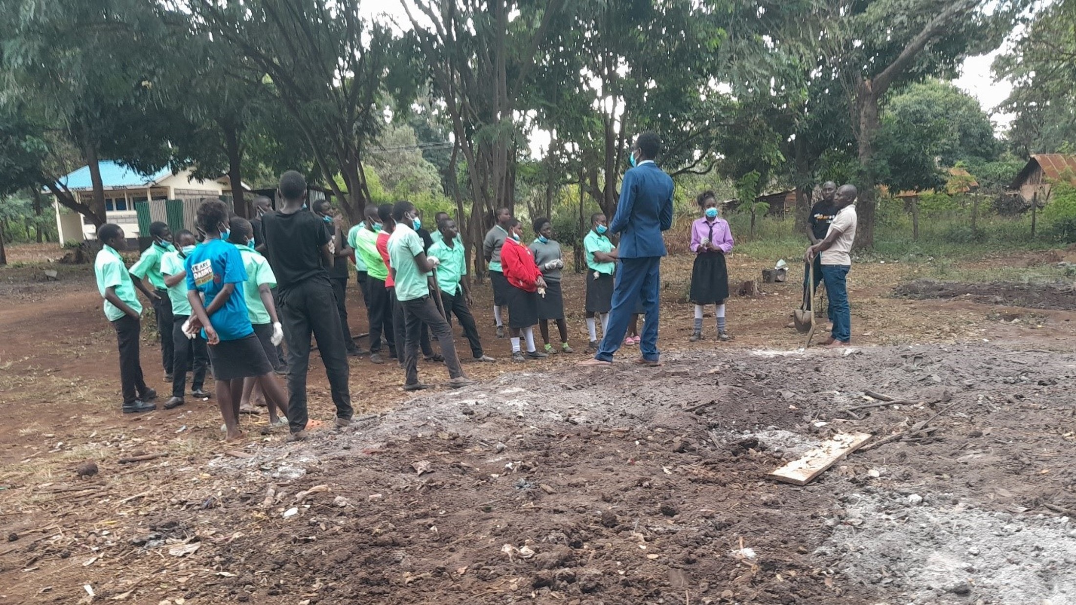 A group of school children standing next to an area of land which they have cleared