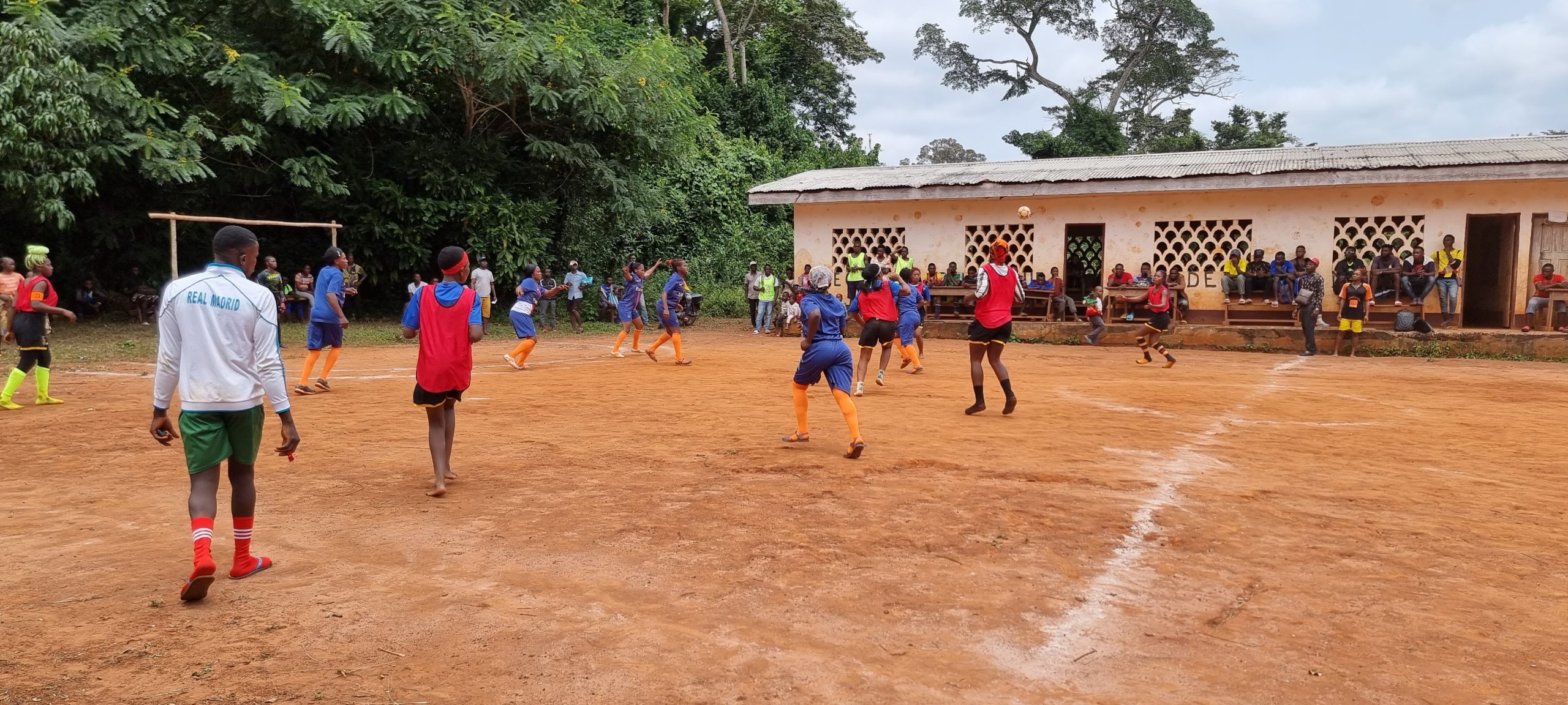 A group of youths playing handball on a dusty pitch