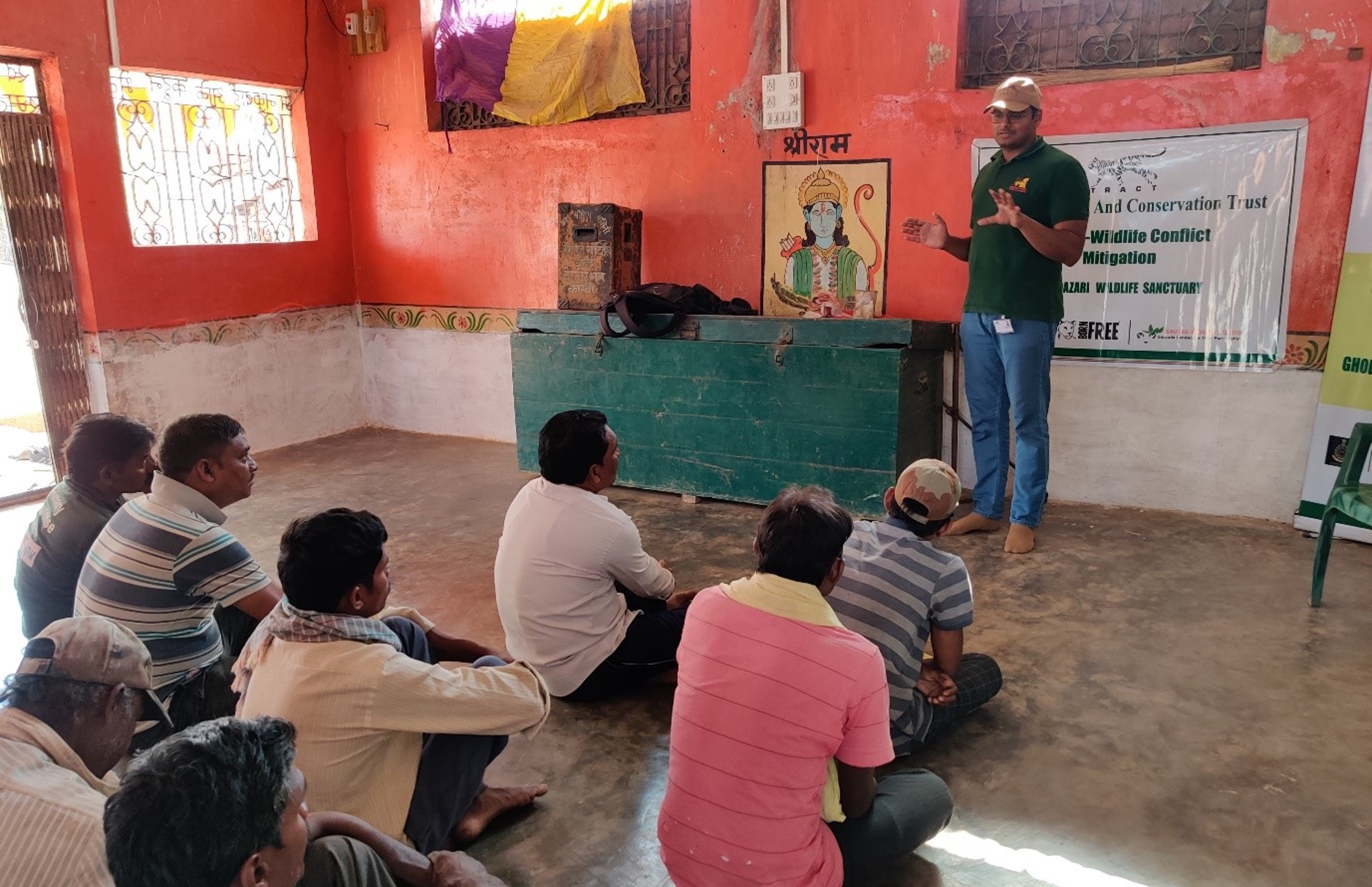 A group of men sitting on the floor in a classroom, listening to a presentation