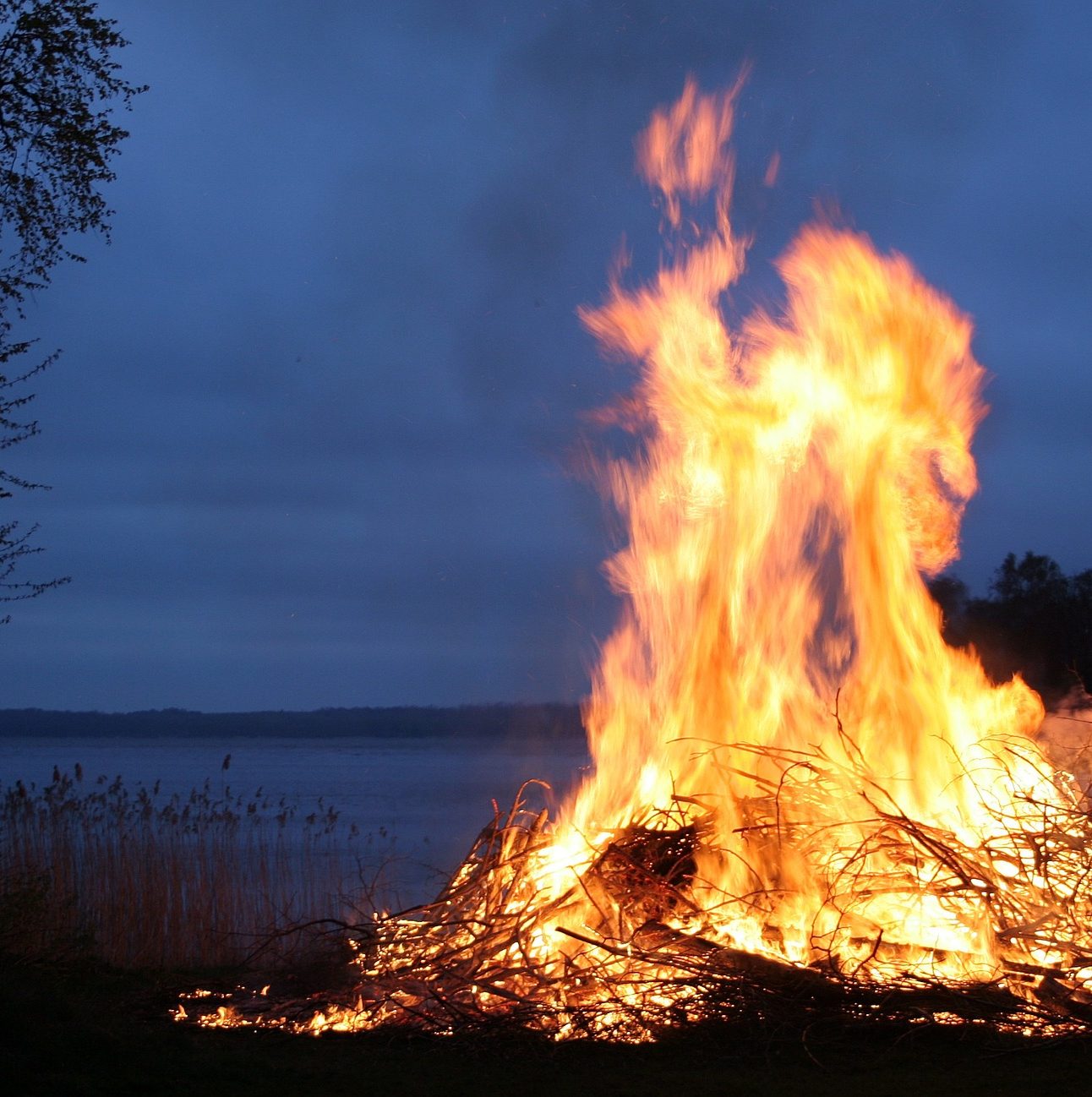 A bonfire alight at night, in front of a lake