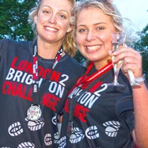 Two women wearing medals and holding glasses of champagne after completing an Ultra Challenge