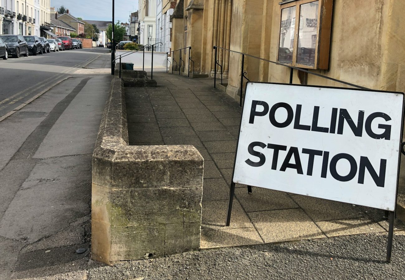 A propped up sign reading 'polling station' in front of a sandstone building