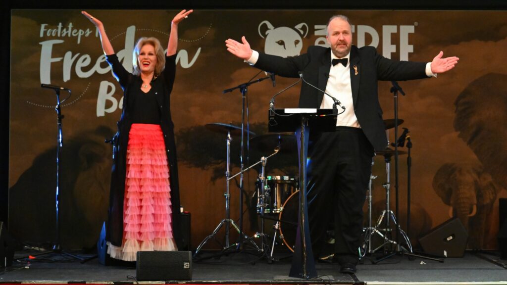 Joanna Lumley and James Lewis standing on a stage with their arms raised in the air
