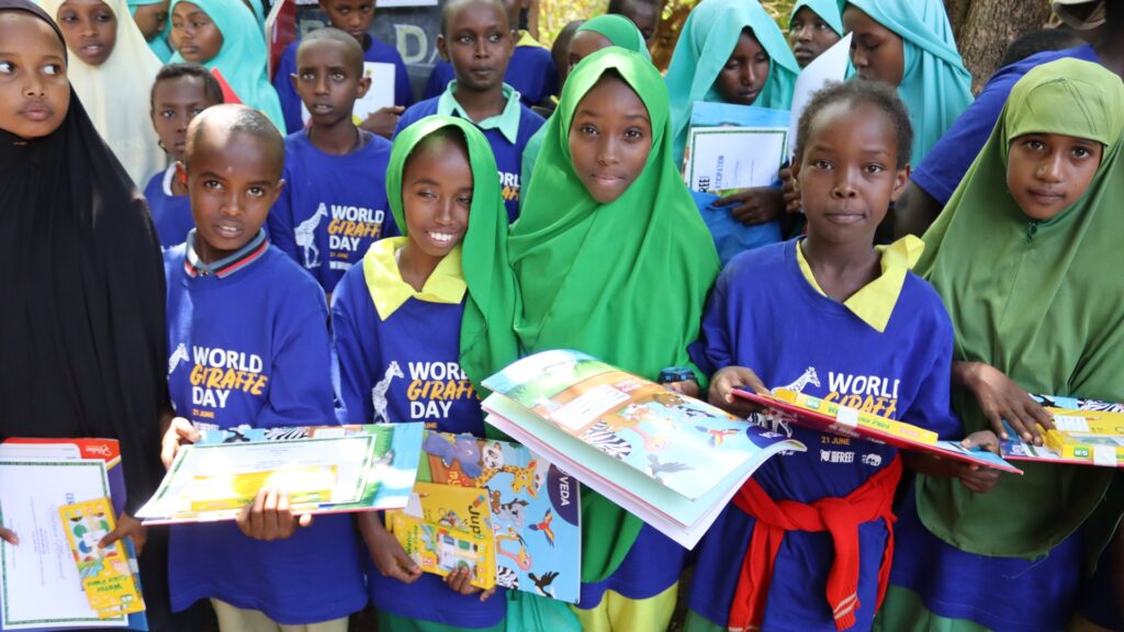 A group of Kenyan schoolchildren wearing Giraffe Day T-shirts and holding workbooks