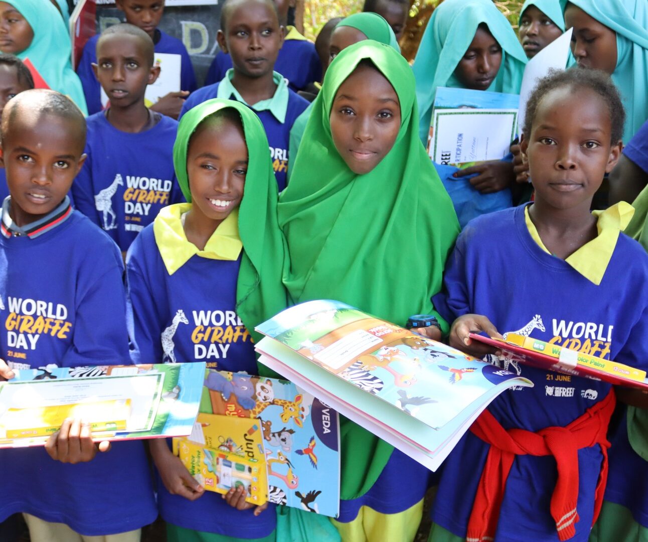 A group of Kenyan schoolchildren wearing Giraffe Day T-shirts and holding workbooks