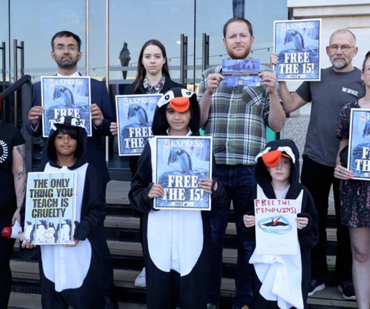 A group of people stand outside Sea Life London Aquarium holding posters.