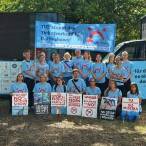 A group of protestors wearing blue T-shirts gather holding placards outside TUI HQ