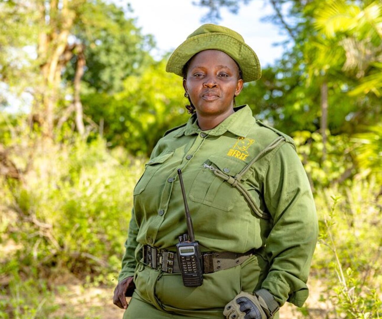 A photo of Jackline Ntinyari in a green uniform standing in an outdoor setting