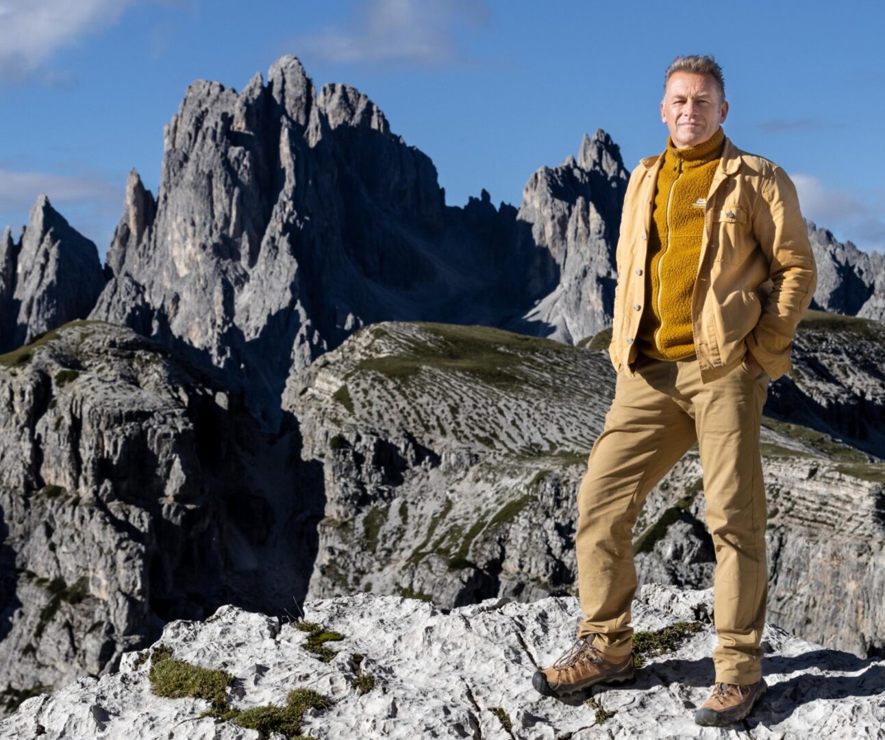 A photo of Chris Packham standing on the top of a snowy mountain