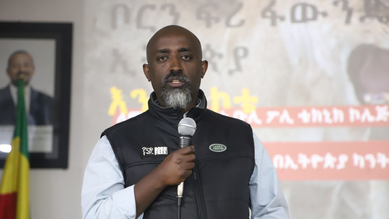 Bereket Girma is standing holding a microphone