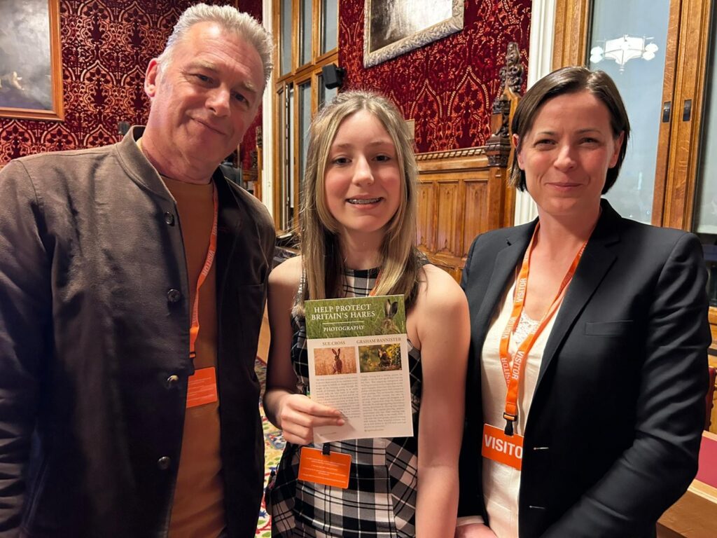 Chris Packham, Thea Caine and Chloe Dalton stood together, Thea holding a poster about hares