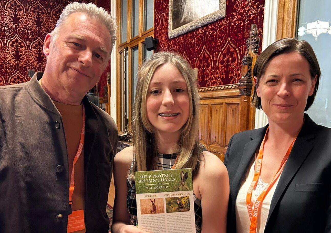 Chris Packham, Thea Caine and Chloe Dalton stood together, Thea holding a poster about hares