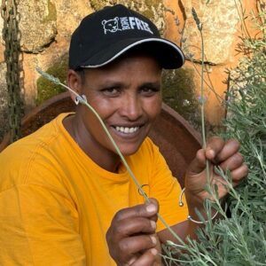 A close-up portrait of Tenagne Teshome holding sprigs of lavender