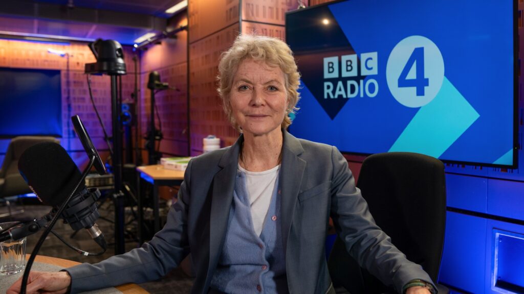 A photo of Jenny Seagrove sitting on a chair at the BBC Radio 4 studio, with microphones visible.