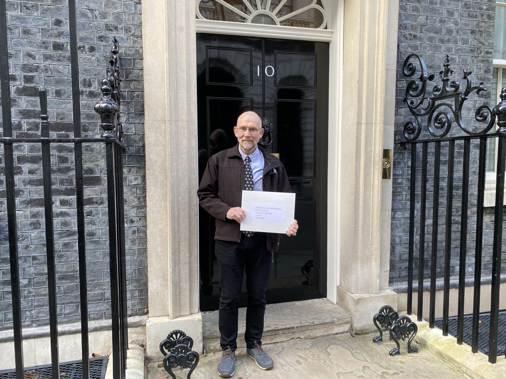 Dr Mark Jones stood in front of 10 Downing Street holding a large letter