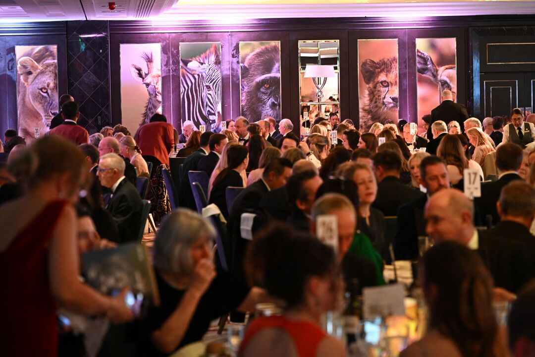 A packed room with George Logan photo panels in the background