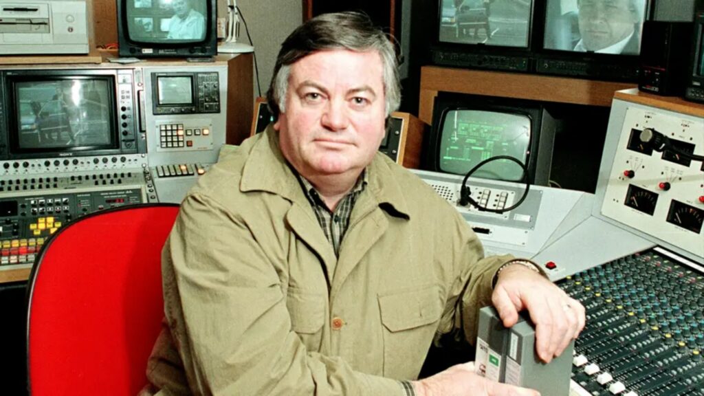 A photo of Roger Cook sitting at a desk in a recording studio