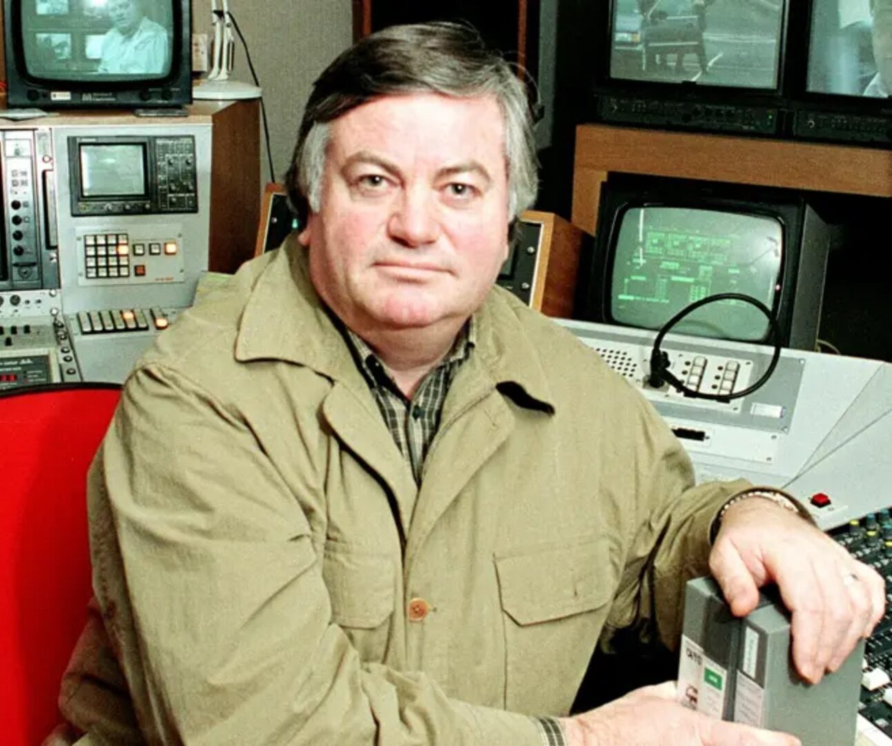 A photo of Roger Cook sitting at a desk in a recording studio