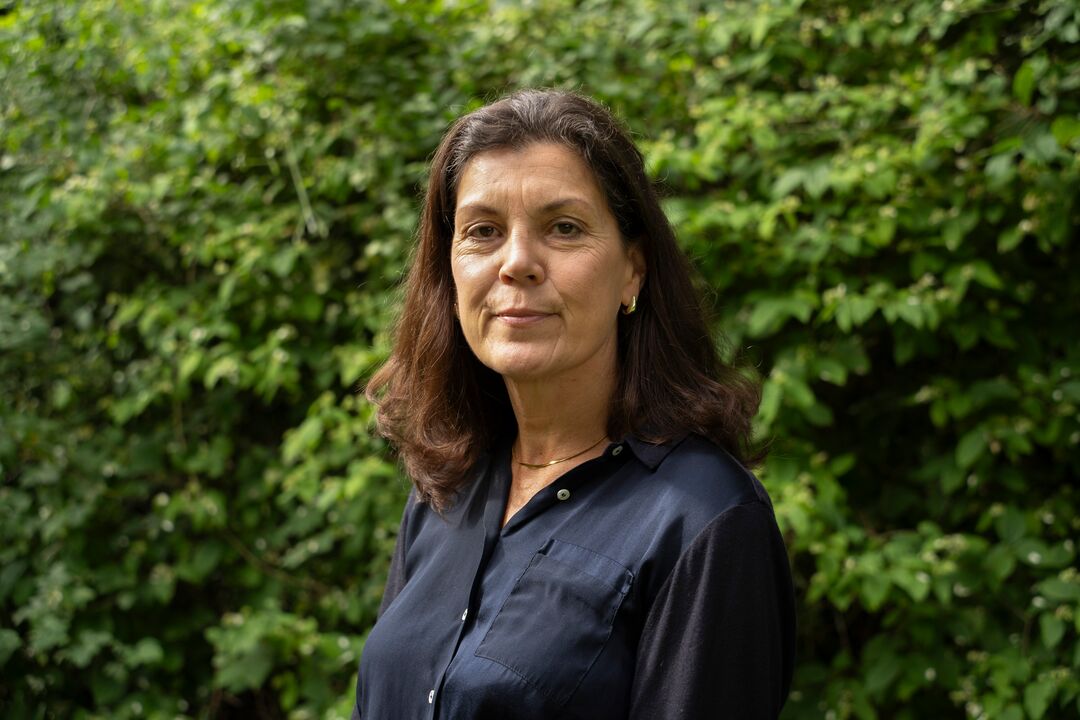 A head and shoulders photo of Helen Bushell with a green leafy background