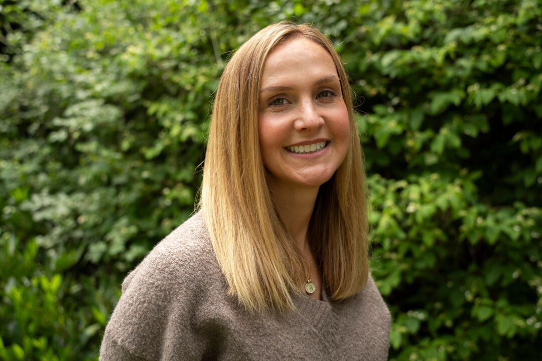 Headshot of Katrina Prentki with a green leafy background